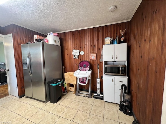 kitchen featuring light tile patterned floors, stainless steel appliances, ornamental molding, and a textured ceiling