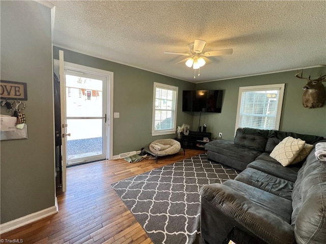 living room featuring ceiling fan, a textured ceiling, wood-type flooring, and baseboards