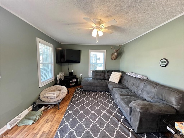 living room with a textured ceiling, ceiling fan, ornamental molding, and wood finished floors