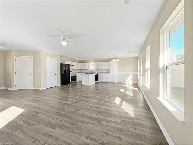 unfurnished living room featuring hardwood / wood-style flooring and ceiling fan with notable chandelier