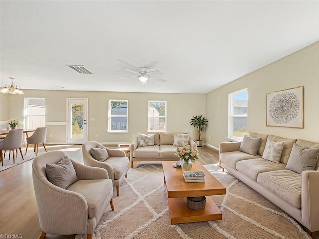 living room with light hardwood / wood-style floors, plenty of natural light, and ceiling fan with notable chandelier