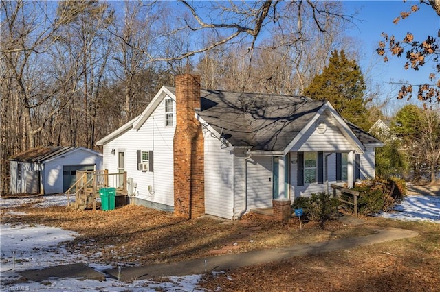 snow covered property with a garage and an outdoor structure