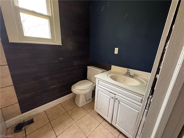 bathroom with tile patterned flooring, wood walls, toilet, and vanity