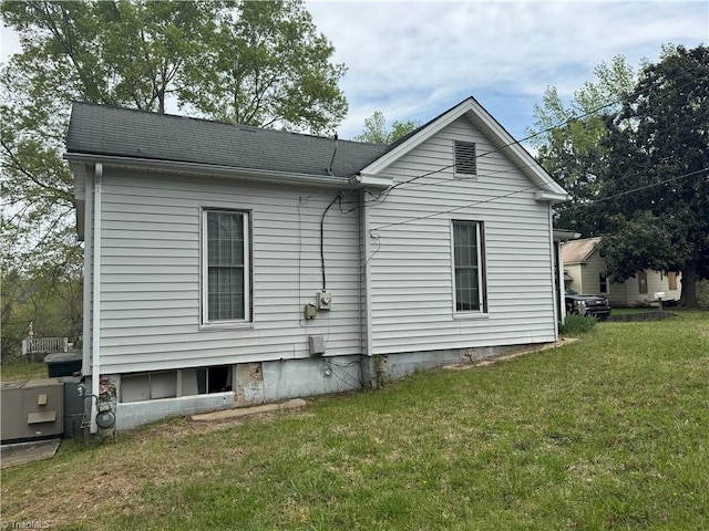 back of house with a shingled roof and a yard