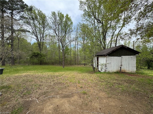 view of yard with an outbuilding, a shed, and a wooded view