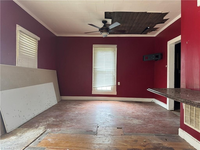 spare room featuring crown molding, baseboards, wood-type flooring, and a ceiling fan