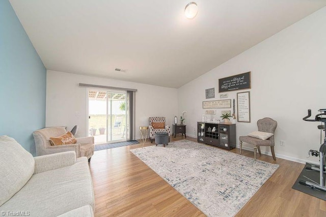 living area with wood finished floors, vaulted ceiling, and baseboards
