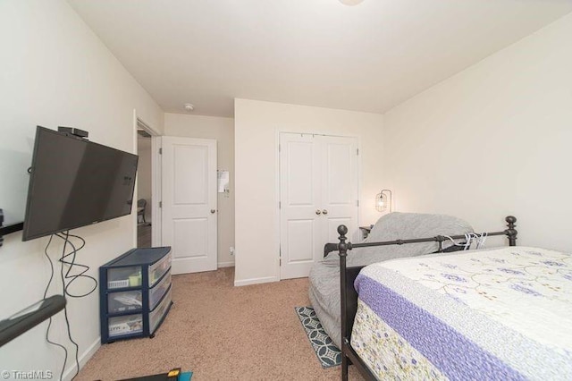 bedroom featuring a closet, light carpet, and baseboards