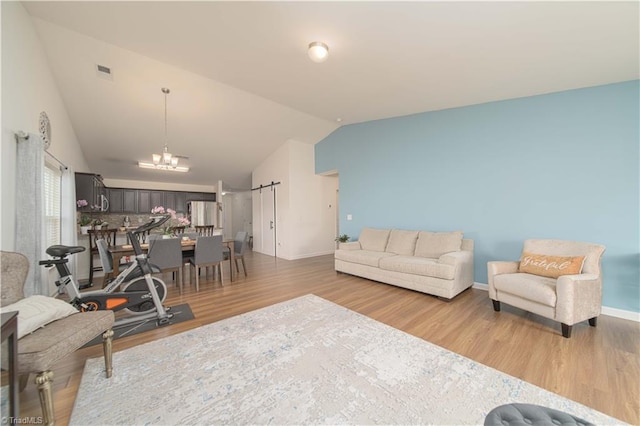 living area featuring wood finished floors, lofted ceiling, a chandelier, and baseboards