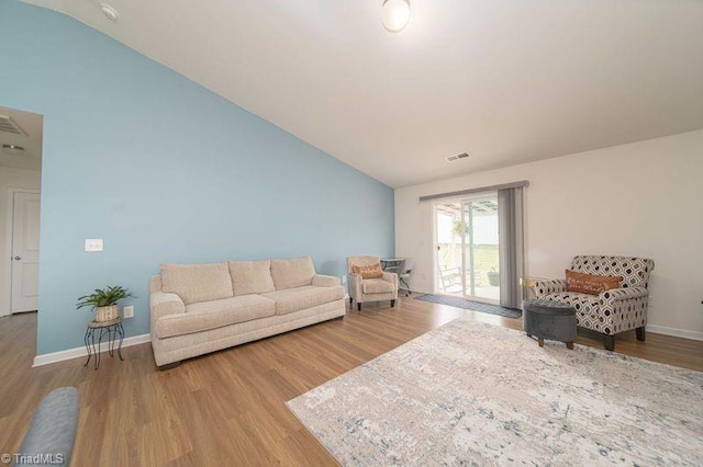 living area featuring lofted ceiling, wood finished floors, and baseboards