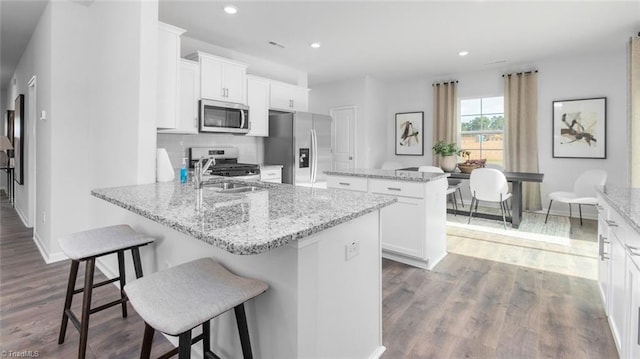 kitchen with stainless steel appliances, a kitchen island, recessed lighting, dark wood finished floors, and a sink