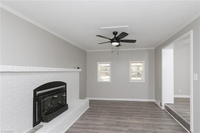 unfurnished living room with a wood stove, ceiling fan, wood-type flooring, and ornamental molding