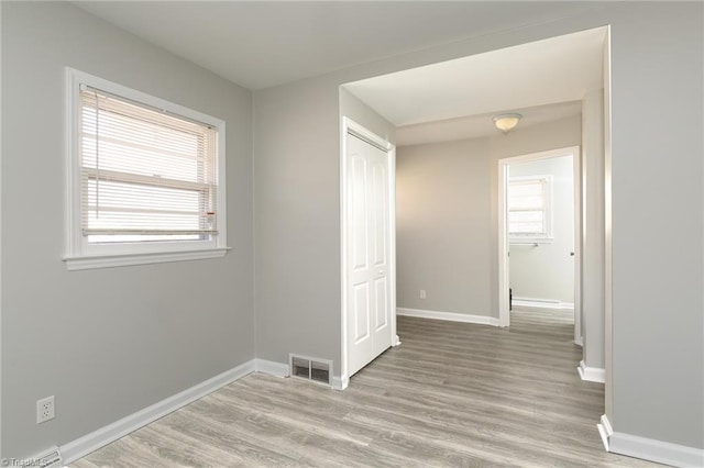 hall with a wealth of natural light and light hardwood / wood-style flooring