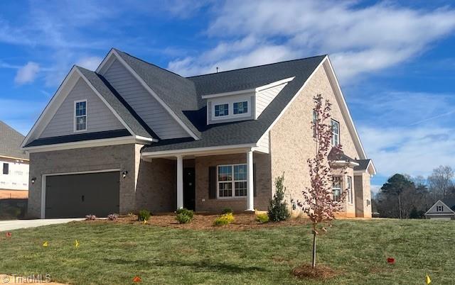 craftsman-style house with a garage, concrete driveway, and a front lawn
