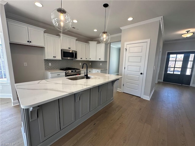 kitchen with white cabinetry, ornamental molding, appliances with stainless steel finishes, a sink, and backsplash