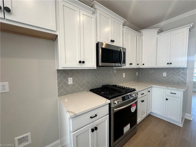 kitchen with white cabinets, light countertops, crown molding, wood finished floors, and stainless steel appliances
