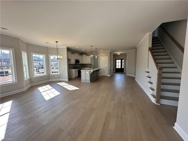 unfurnished living room featuring crown molding, baseboards, and wood finished floors
