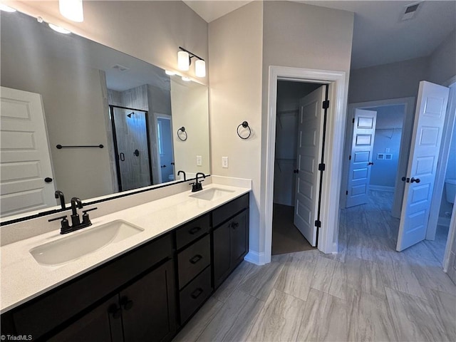full bath with a sink, visible vents, a shower stall, and double vanity