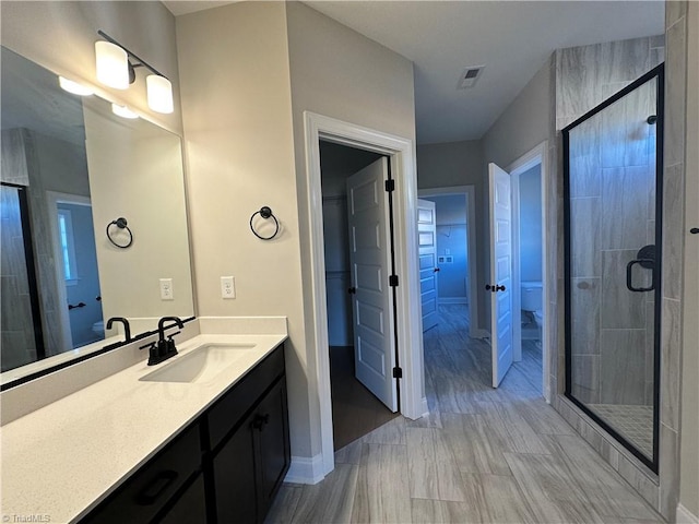 full bath with visible vents, baseboards, a spacious closet, vanity, and a stall shower