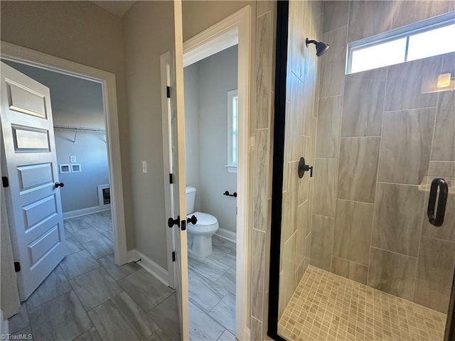 bathroom with toilet, a shower stall, marble finish floor, and baseboards