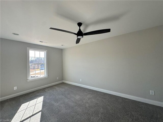 unfurnished room featuring dark carpet, baseboards, a ceiling fan, and visible vents
