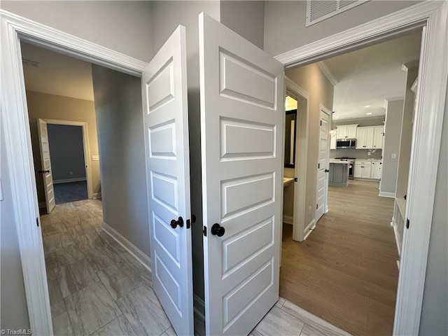 corridor featuring crown molding, baseboards, and visible vents