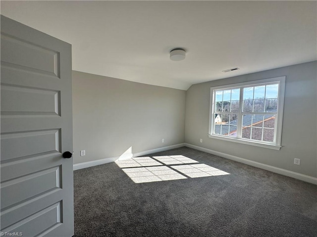 carpeted empty room with visible vents, baseboards, and vaulted ceiling