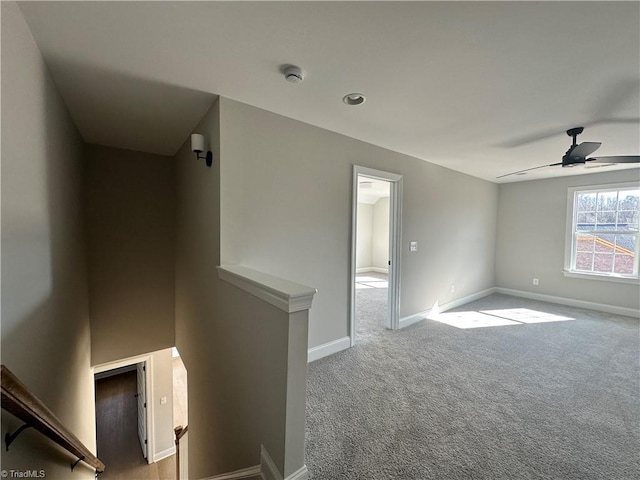 carpeted empty room featuring baseboards and ceiling fan