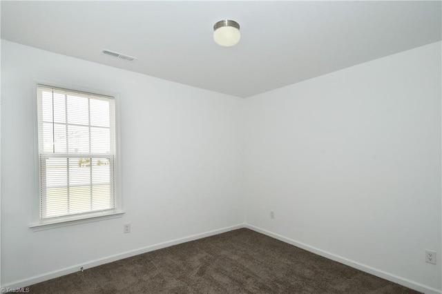 spare room with dark carpet