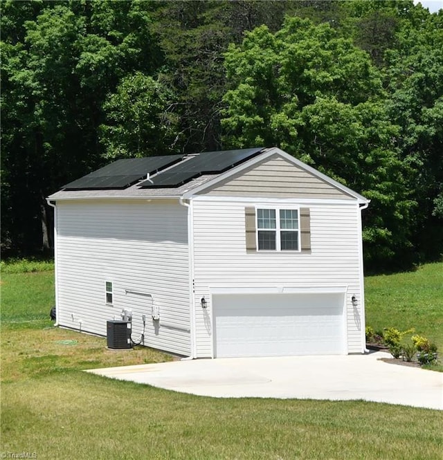 view of home's exterior with central AC, a garage, a lawn, and solar panels