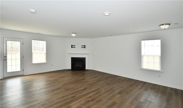 unfurnished living room featuring a healthy amount of sunlight and dark hardwood / wood-style flooring