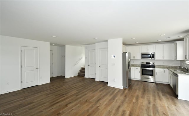 kitchen with stainless steel appliances, light stone countertops, sink, and white cabinets