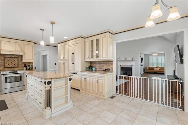 kitchen with hanging light fixtures, stainless steel electric range oven, cream cabinetry, and backsplash