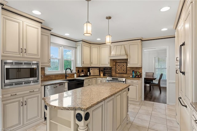 kitchen featuring backsplash, appliances with stainless steel finishes, decorative light fixtures, and a center island