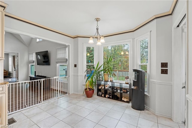 interior space with ornamental molding, a chandelier, vaulted ceiling, and light tile patterned floors