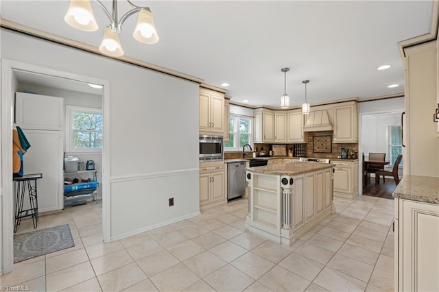 kitchen featuring cream cabinetry, stainless steel appliances, hanging light fixtures, and a kitchen island