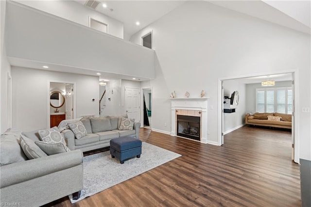 living room featuring hardwood / wood-style flooring, a tiled fireplace, and high vaulted ceiling