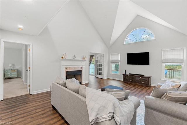 living room featuring dark hardwood / wood-style flooring, high vaulted ceiling, and a tile fireplace