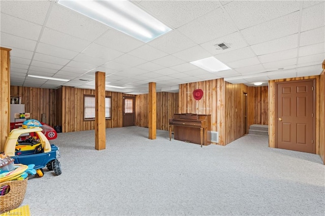 basement with wood walls, carpet floors, and a drop ceiling