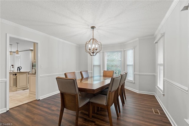 dining area with ornamental molding, wood-type flooring, and a textured ceiling