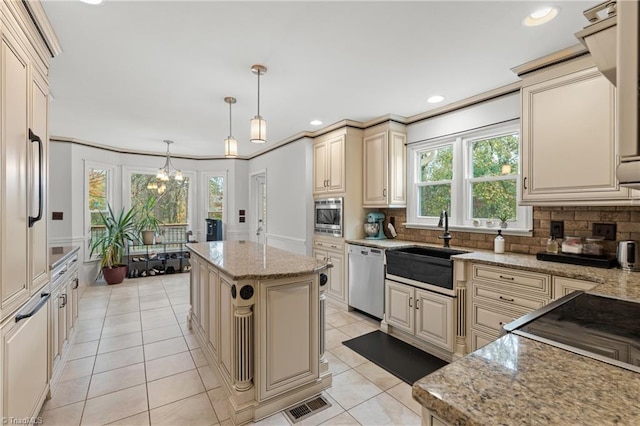 kitchen featuring stainless steel appliances, cream cabinets, a kitchen island, backsplash, and pendant lighting