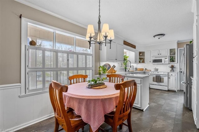 dining area with a wainscoted wall, a textured ceiling, and crown molding