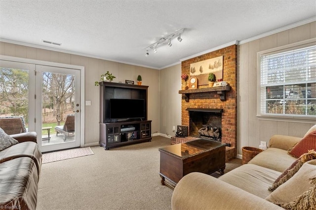 living room featuring visible vents, carpet, ornamental molding, a fireplace, and a textured ceiling