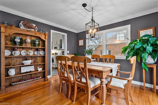 dining room with crown molding, baseboards, an inviting chandelier, wood finished floors, and a textured ceiling