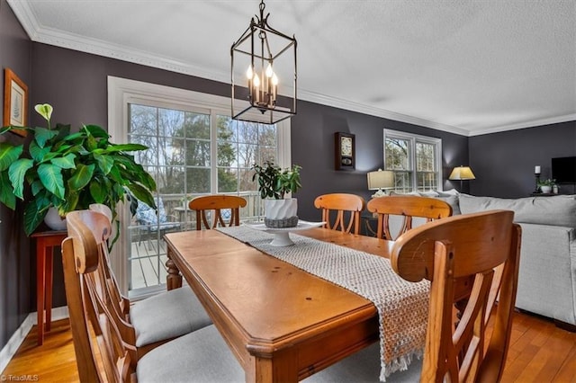 dining area featuring a chandelier, a textured ceiling, crown molding, and wood finished floors