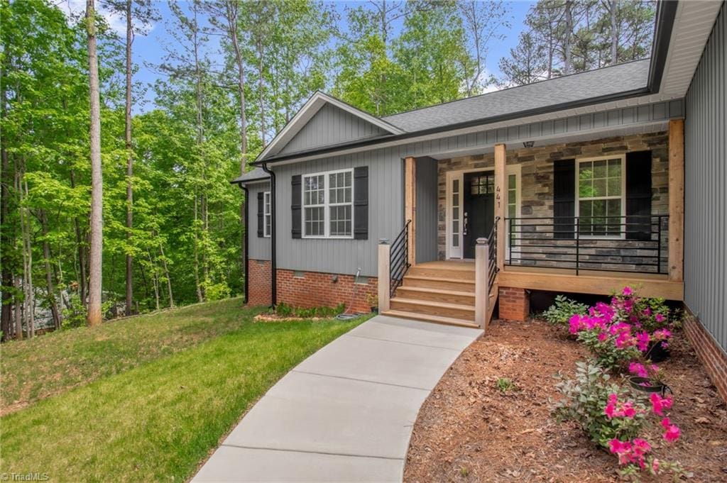 view of front facade with a porch, a front lawn, crawl space, and a shingled roof