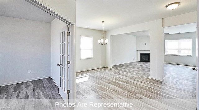 unfurnished living room with a notable chandelier and wood-type flooring