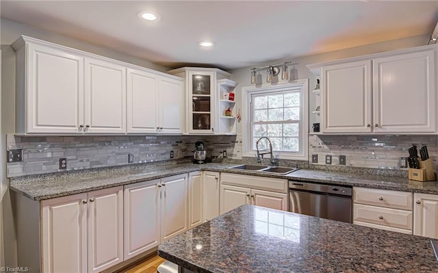 kitchen featuring dark stone countertops, white cabinetry, stainless steel dishwasher, and sink