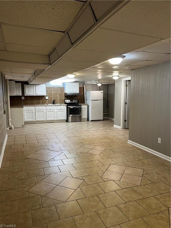 kitchen with white cabinetry, electric range, white refrigerator, wood walls, and a paneled ceiling