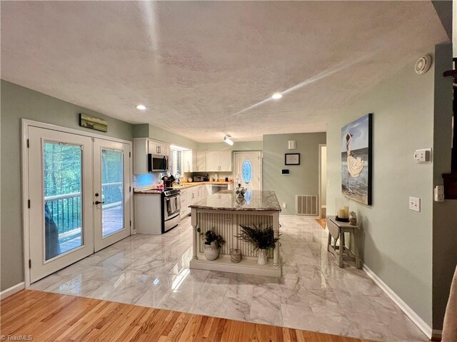 kitchen featuring french doors, stainless steel appliances, white cabinetry, visible vents, and a kitchen island